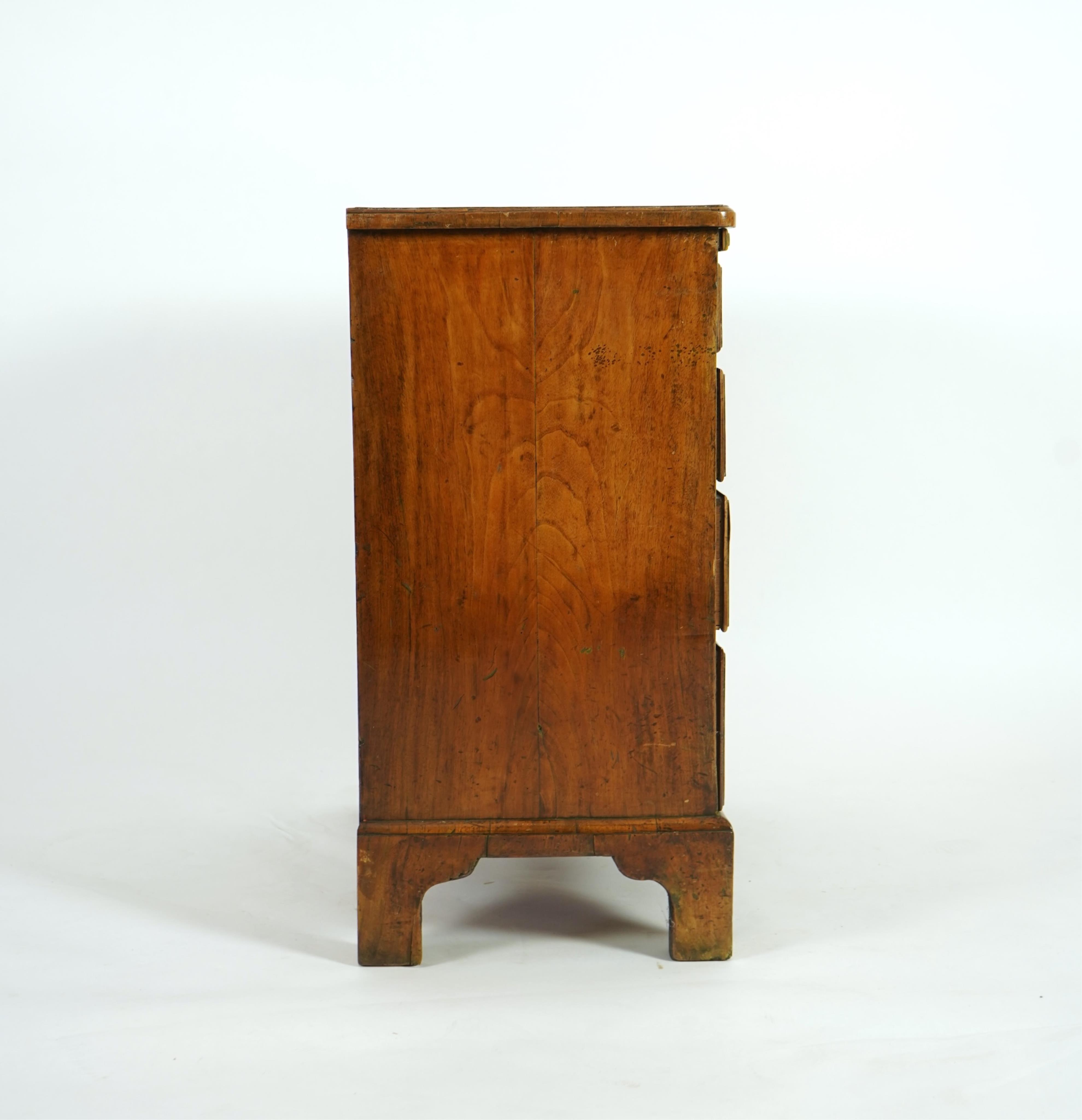 A small early 18th century and later cross and feather banded walnut veneered chest